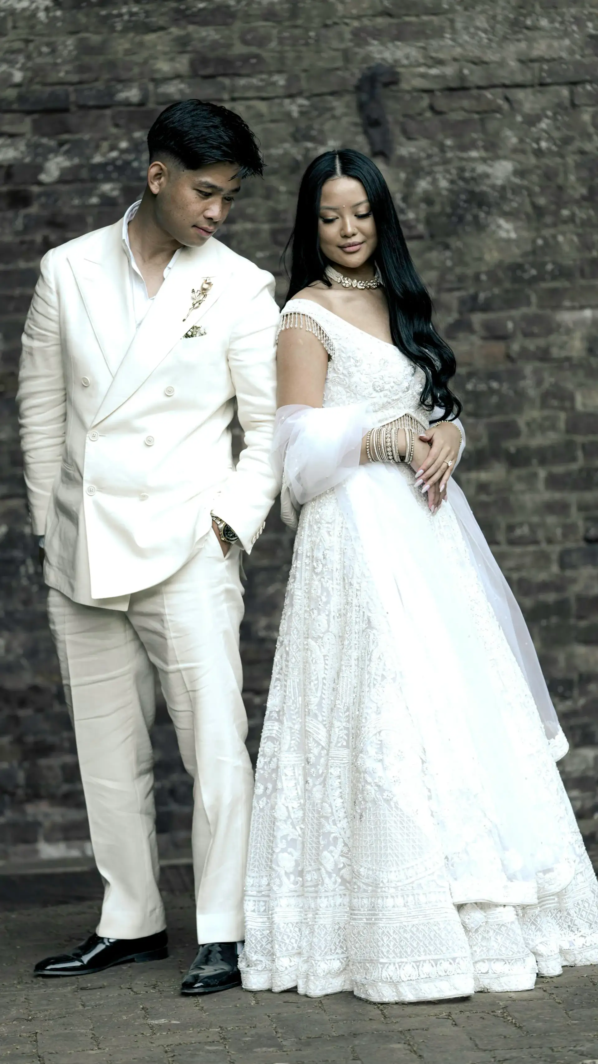 Ela and Neel, in ivory, against a dark brick wall